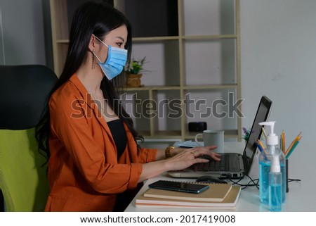Asian women work at home. To confine yourself during the corona virus By wearing a mask and washing her hand sanitizing to prevent Covid-19