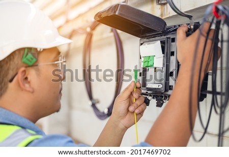 An internet technician is repairing or maintaining a fiber optic connection by opening a fiber optic connector. Royalty-Free Stock Photo #2017469702