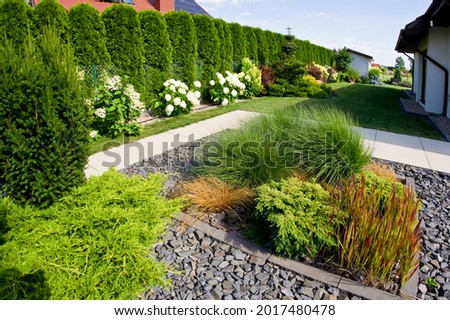 The frontyard of a modern house, garden details with colorful plants, dry grass beds surrounded by grey rocks. Royalty-Free Stock Photo #2017480478