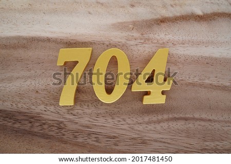 Golden Arabic 704 numerals on a brown to white patterned wooden background.