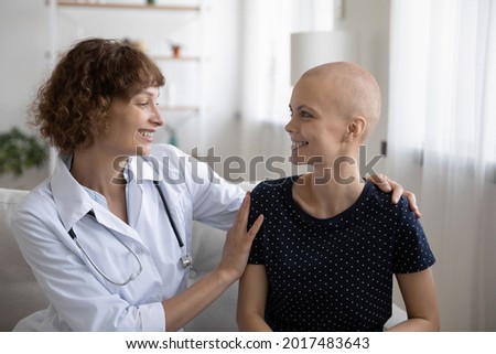 Happy young female doctor cuddling shoulders of smiling bald woman patient with cancer illness, giving psychological support, encouraging during oncology treatment, sharing good treatment news. Royalty-Free Stock Photo #2017483643