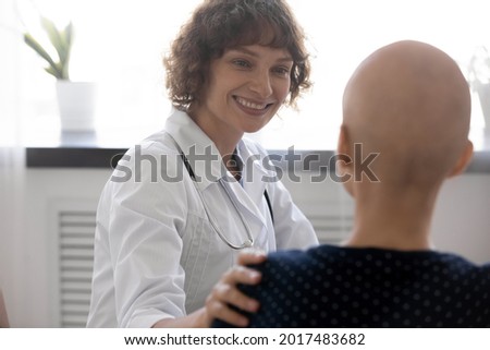 Happy young compassionate kind female oncologist doctor supporting bald after chemotherapy patient woman, telling effective treatment good news or giving psychological support at checkup meeting. Royalty-Free Stock Photo #2017483682
