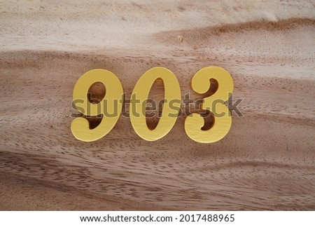 Golden Arabic 903 numerals on a brown to white patterned wooden background.