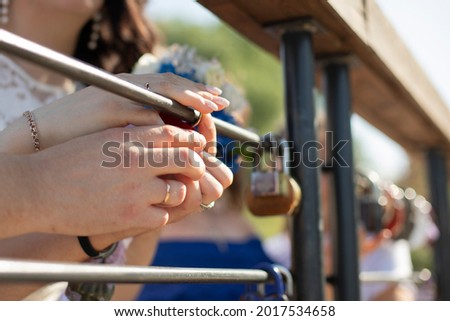 The newlyweds snap the lock. A guy and a girl hang up the lock as a sign of eternal love. Lovers are holding a symbol of love.