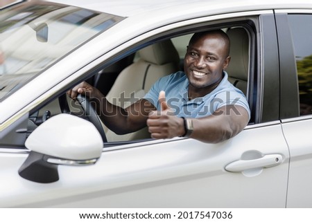 Car showroom, auto retail concept. Happy black man in casual outfit driving luxury white car, showing thumb up, african american driver enjoying brand new comfortable automobile, copy space