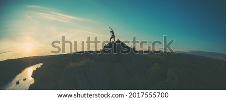 Woman on top of a cliff, silhouette of a girl on top of a mountain, sunset in a beautiful place, travel to picturesque places