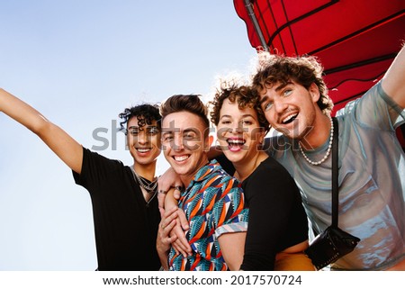 Young group of friends having fun together outdoors. Four happy queer people smiling cheerfully while standing together and embracing each other. Friends bonding and spending time together. Royalty-Free Stock Photo #2017570724