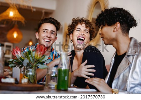 Young group of friends laughing cheerfully in a restaurant. Four young queer people having fun together during lunch. Friends bonding and spending time together. Royalty-Free Stock Photo #2017570730
