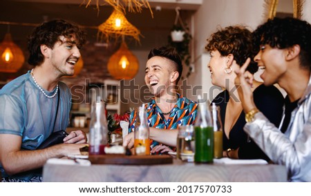 Carefree group of friends laughing together in a restaurant. Four young queer people having fun together during lunch. Friends bonding and spending time together. Royalty-Free Stock Photo #2017570733