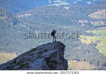 Young male photographer standing on top of the mountain taking pictures
