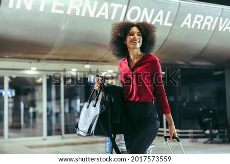 Smiling African woman with luggage walking at international airport. Happy female on international business Royalty-Free Stock Photo #2017573559