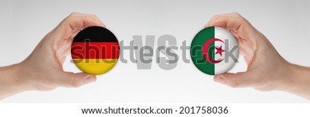 Man's hands holding styrofoam balls with German and Algerian flag against the white background.