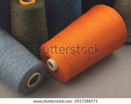 Cones of colored cotton, woolen or synthetic threads. Bobbins of yarn using in textile manufacturing and for handmade products, copy space Royalty-Free Stock Photo #2017588571