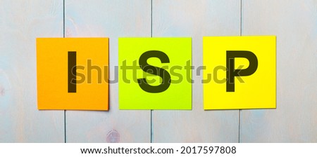 Three colored stickers with the text ISP Internet Service Provider on a light blue wooden background