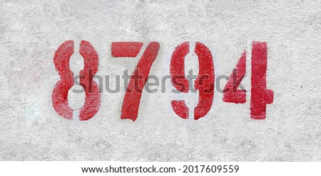 Red Number 8794 on the white wall. Spray paint. Number eight thousand seven hundred ninety four.