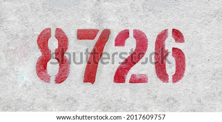 Red Number 8726 on the white wall. Spray paint. Number eight thousand seven hundred and twenty six.