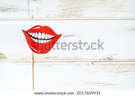 Party Stick with Paper Red Lips with Smile on a White Wooden Background 