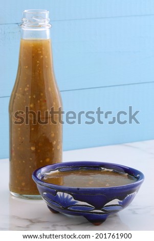 Artisan mexican tomatillo salsa in vintage talavera bowl, with a delicious fresh hot flavor,  on vintage carrara marble table.