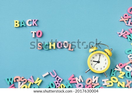 Text Back To School. Many multicolored letters and alarm clock. School studies, teaching to read.