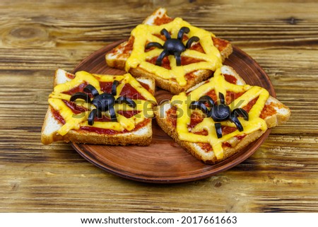 Funny sandwiches with spider and spider web for Halloween party on wooden table