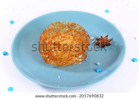Ice cream in sugar caramel on a blue plate.