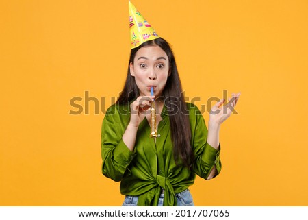 Shocked fun amazed young brunette asian woman wearing basic green shirt birthday hat stand blow in pipe spreading hands looking camera isolated on bright yellow colour background studio portrait 8 14 Royalty-Free Stock Photo #2017707065