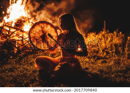 beautiful shamanic girl playing on shaman frame drum in the nature. Royalty-Free Stock Photo #2017709840
