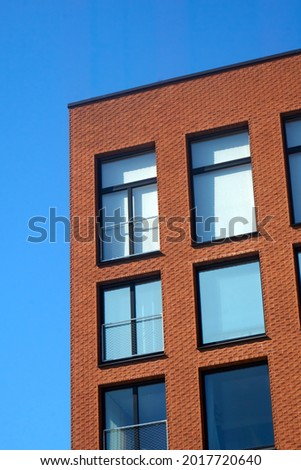 Red brick wall of a modern building against bright blue, clear sky on a sunny day. . High quality photo