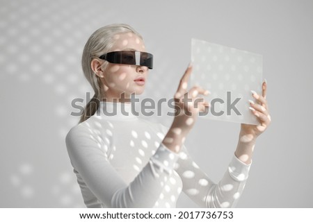 Young woman in glasses holds futuristic gadget Royalty-Free Stock Photo #2017736753