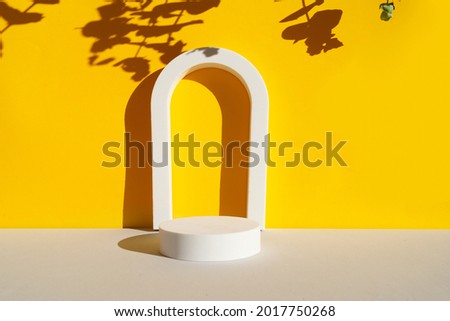 Minimal modern product display with arches on textured gray and yellow background with leaves shadows overlay