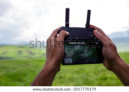 Male hands holding generic design dron remote controller doing some setings ready to run it into the sky.