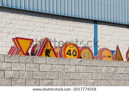 Road signs used for road repairs are stacked in a row at a construction warehouse.