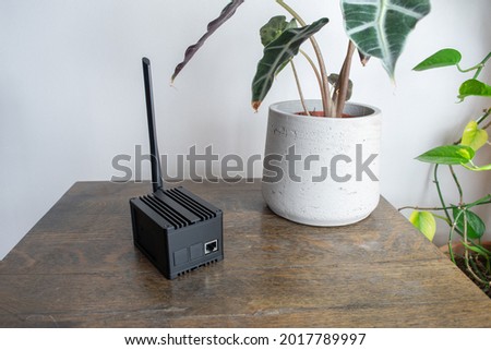 Helium hotspot cryptocurrency miner next to a plant in a home or office. Royalty-Free Stock Photo #2017789997