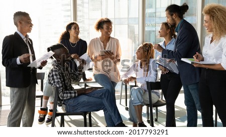 Happy young african american female leader holding negotiations meeting with friendly diverse colleagues gathered at table in modern office room, discussing project ideas or developing strategy. Royalty-Free Stock Photo #2017793291