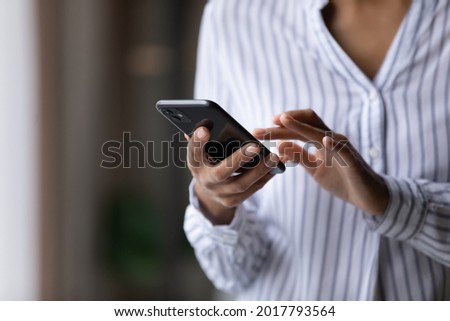Crop close up of African American woman hold cellphone text message online on gadget. Ethnic biracial female use smartphone browse surf wireless internet on device. Technology, communication concept. Royalty-Free Stock Photo #2017793564
