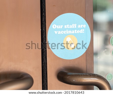 Vaccinated poster at door entrance of restaurant in Waco, Texas, America. Our staff are vaccinated sticker for coronavirus at entry way door handle.