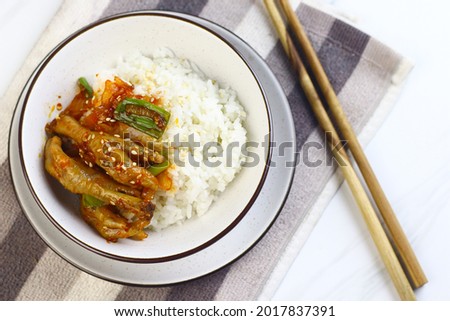 Korean Spicy Chicken feet or ceker ayam saus Gochujang served on white plate with sesame seed and slices onion spring. Bright mood food photography.
