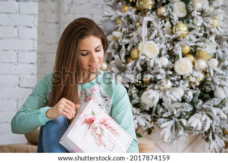 a young brunette woman in a festive interior near the Christmas tree.
