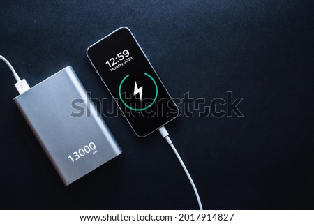 Charging power bank. Portable powerbank with white usb cable for charger mobile phone or smartphone battery. Modern technology concept in top view Royalty-Free Stock Photo #2017914827