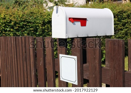 White metal mailbox mounted on a rustic  fence 