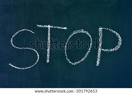the word stop written with chalk on a chalkboard