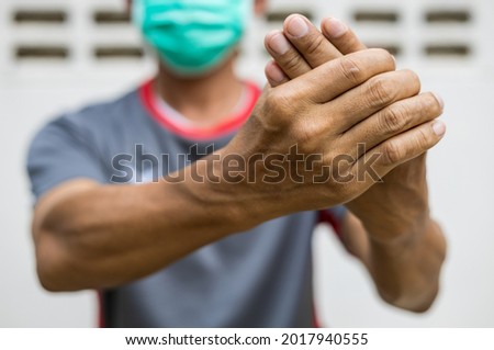 Close-up of two hands of a man squeezing in a massage due to nerve endings numbness in guillain barre syndrome, a possible side effect of the COVID-19 vaccination.