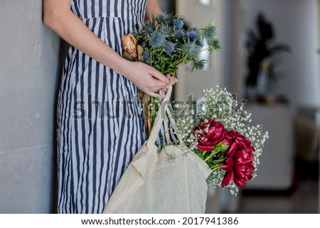 Female with  tote bag and Gypsophila paniculata, Eryngium, and peonies flowers on white background.