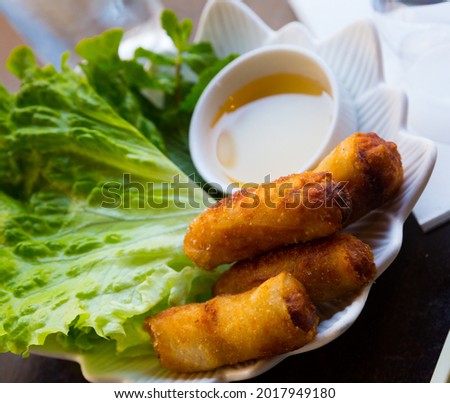 Traditional Cambodian dish Nem ran - crispy fried rolls in rice paper served with sauce and fresh greens