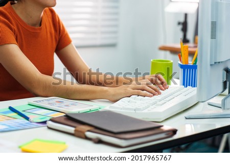 Woman working on computer on desk in office.