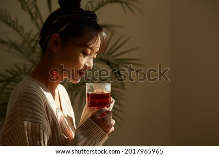A young Asian woman relaxing at home drinking fruit tea Royalty-Free Stock Photo #2017965965