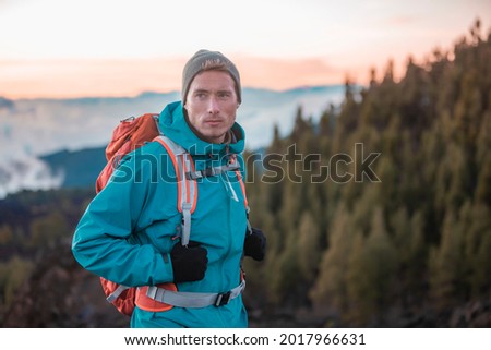 Man hiker hiking in mountain forest wearing cold weather accessories, wind jacket and backpack for camping outdoor. Guy portrait lifestyle. Royalty-Free Stock Photo #2017966631