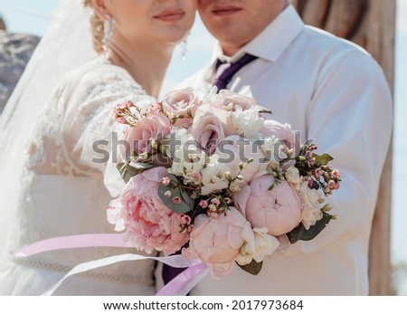Picture of man and woman with bouquet. Married couple holding hands, ceremony wedding day. Newly wed couple's figures.