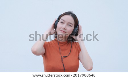 attractive stylish asian woman listening music in headset on white background. closeup portrait happy female relaxing playing song playlist via headphone. entertainment technology smiling. half length Royalty-Free Stock Photo #2017988648
