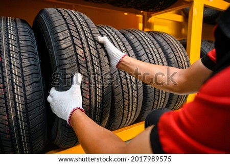 male tire changer In the process of checking the condition of new tires that are in stock to be replaced at a service center or auto repair shop Tire depot for the automobile industry